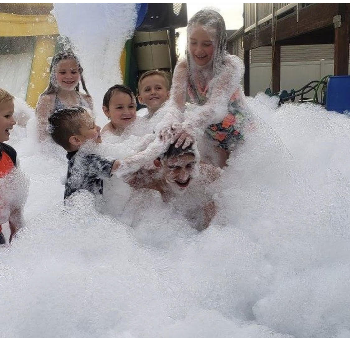 Group of kids playing together in a mountain of foam in a backyard
