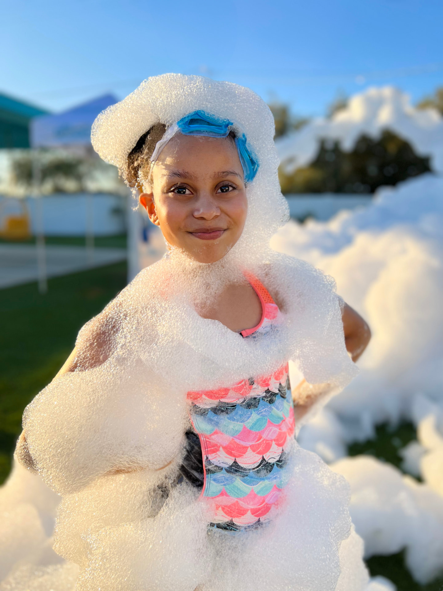 Smiling girl wrapped in a blanket of foam at a backyard foam party