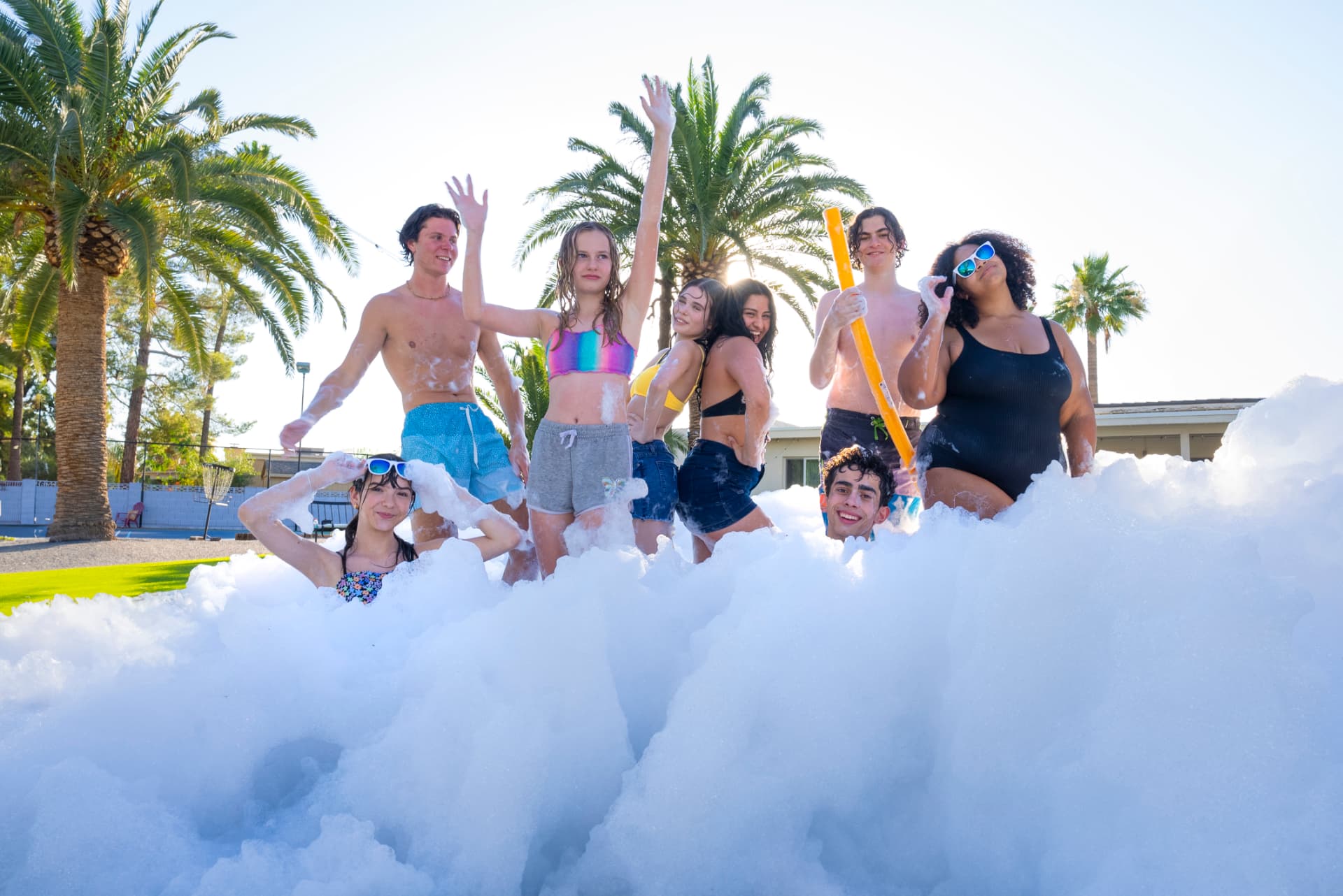 Teens posing in a wall of foam at an outdoor foam party