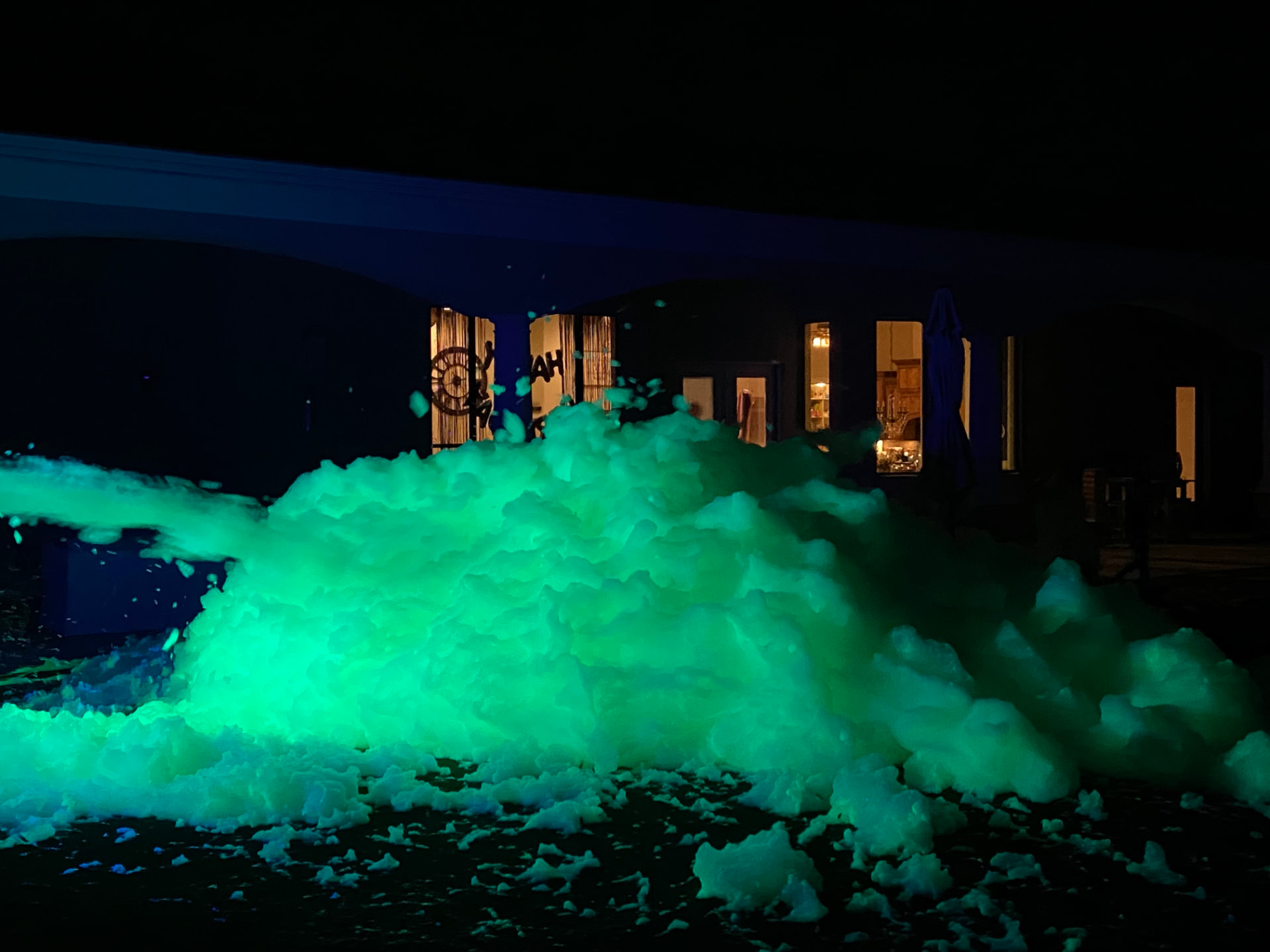Neon green glow foam filling a backyard at night for an evening glow party