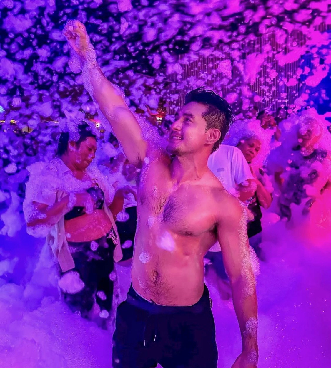 Guest celebrating with an arm raised in purple-lit glow foam at a nighttime special event
