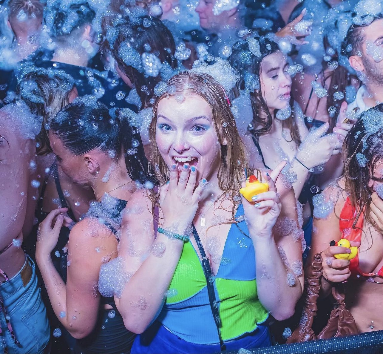 Crowd covered in blue-lit foam bubbles at a packed special event foam party
