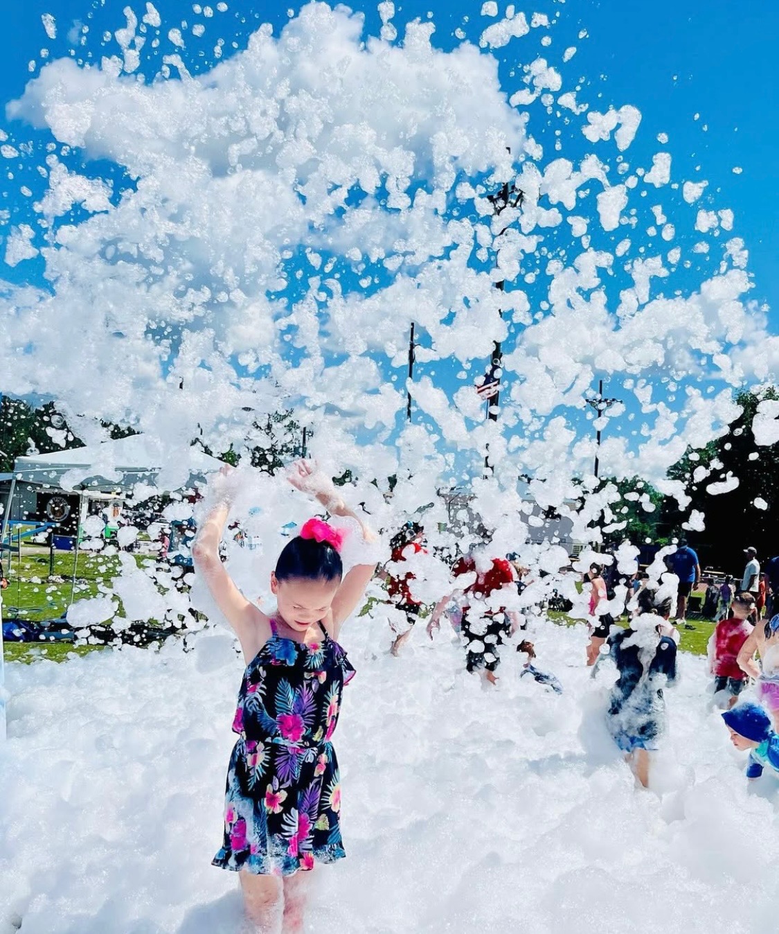 Foam cannon blasting a huge cloud of foam over kids at an outdoor park foam party