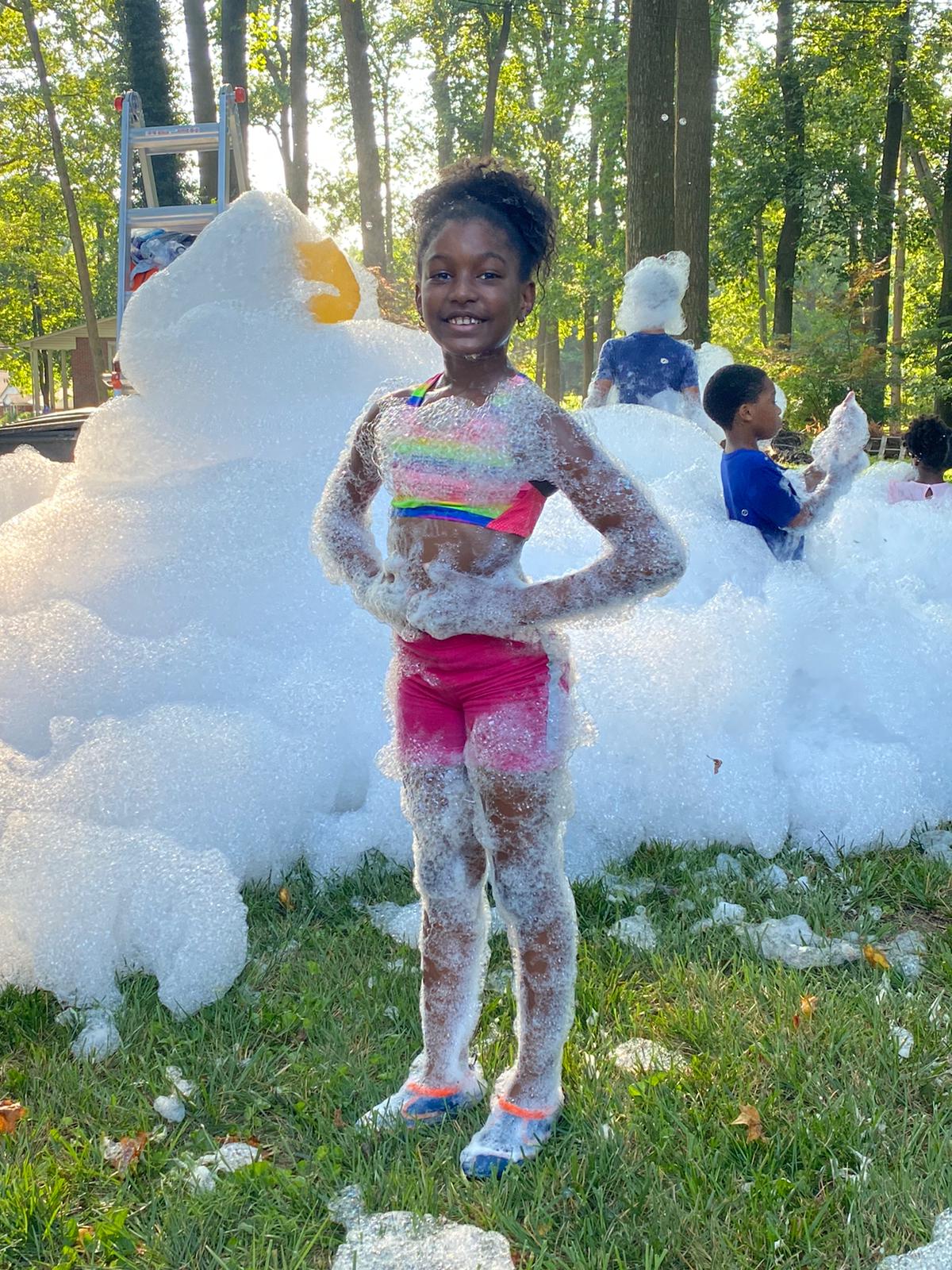 Girl posing in front of a mountain of foam at a backyard party