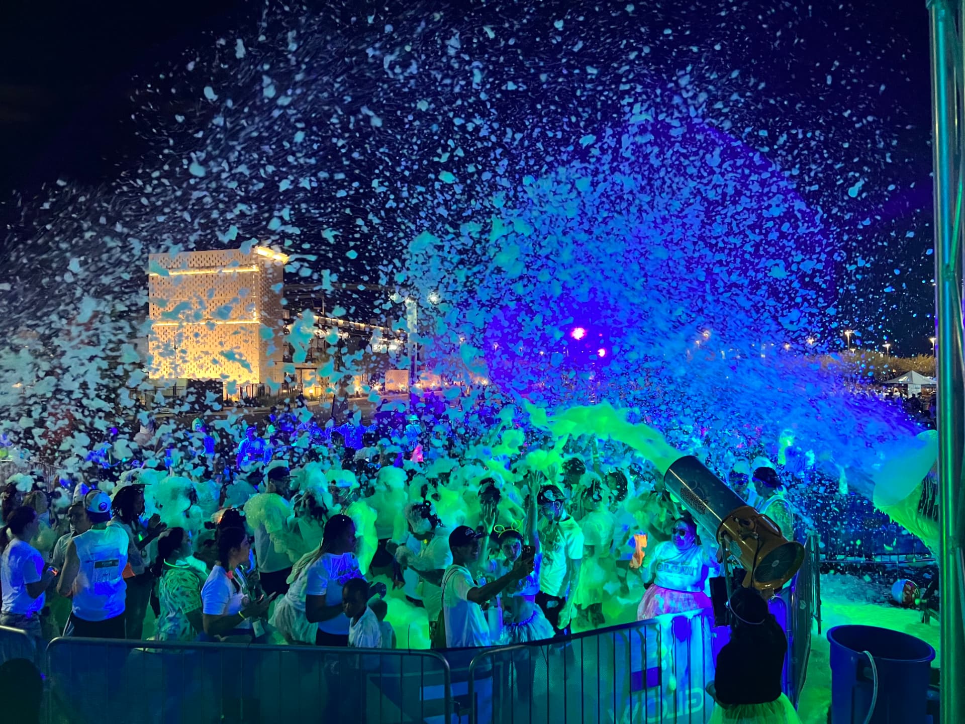 Community glow foam event in Cincinnati with a large festival crowd under glowing foam