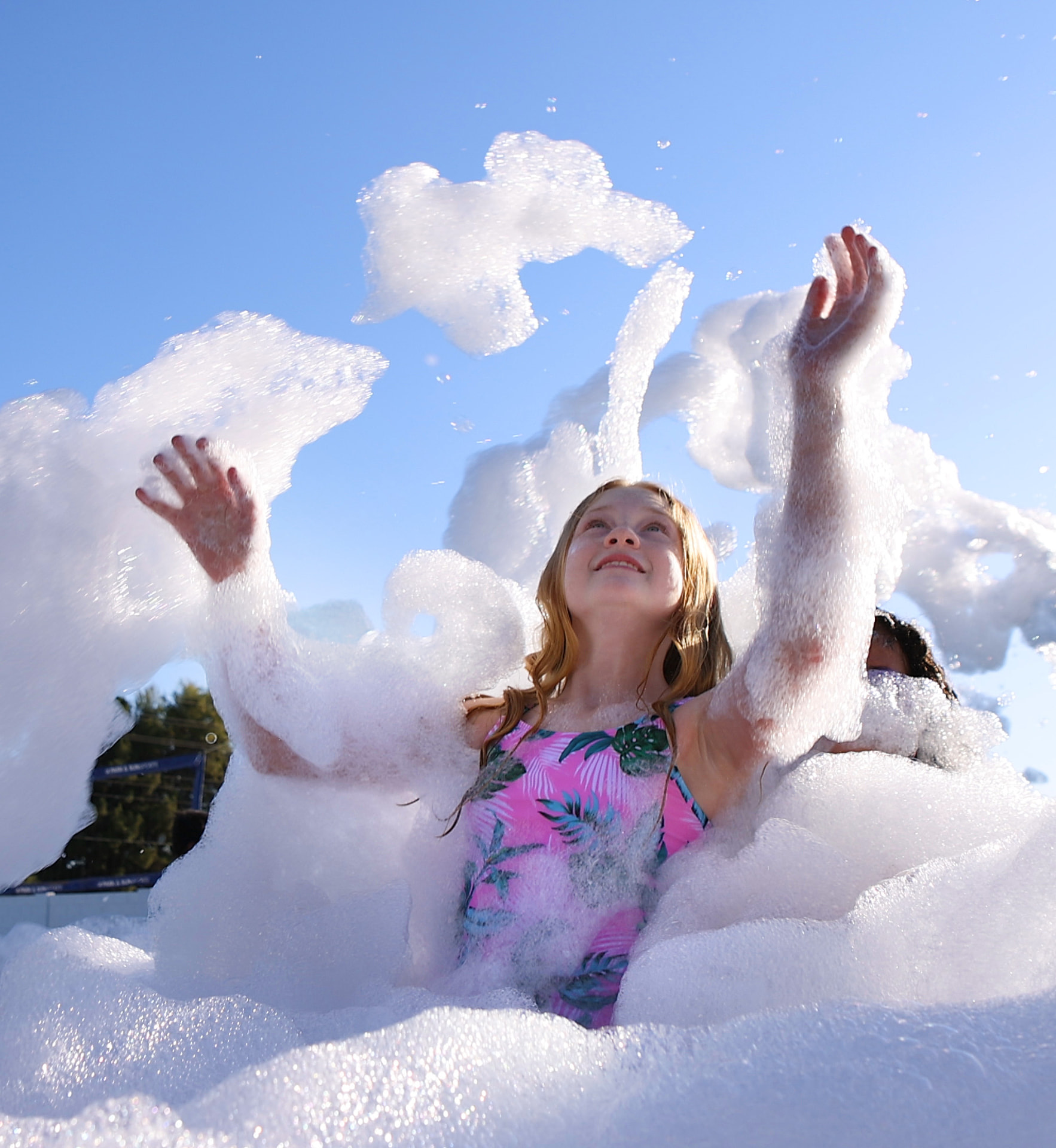 Girl tossing foam into the air on a sunny day at a foam party